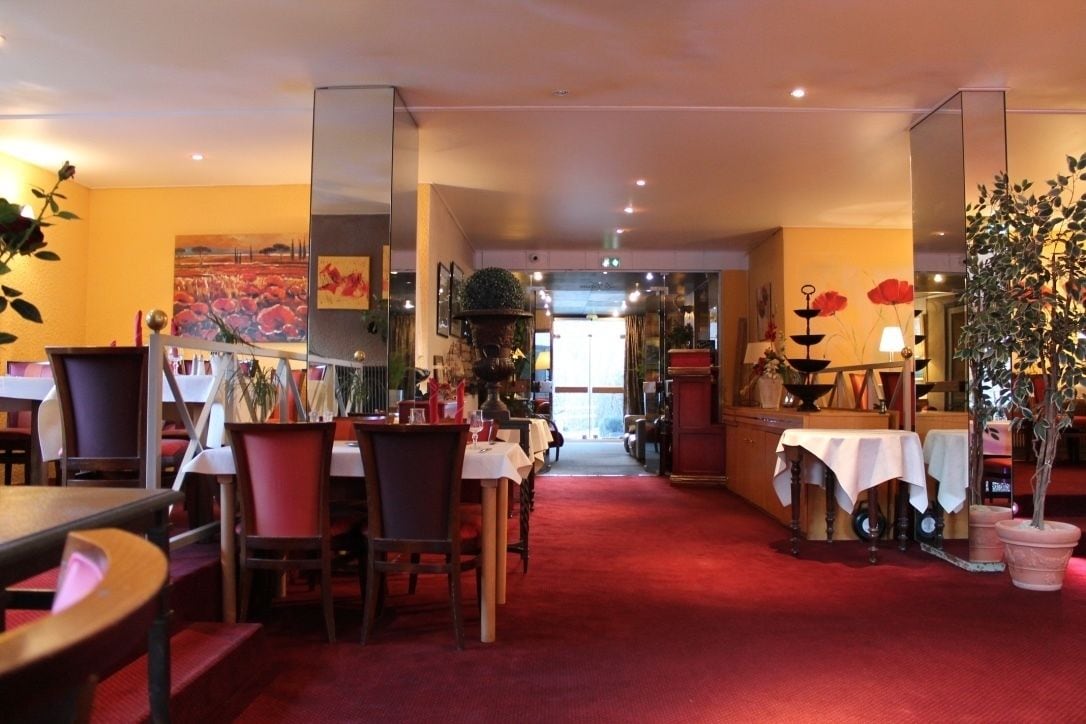Un restaurante con mesas y sillas, una alfombra roja y un ventanal grande al fondo.