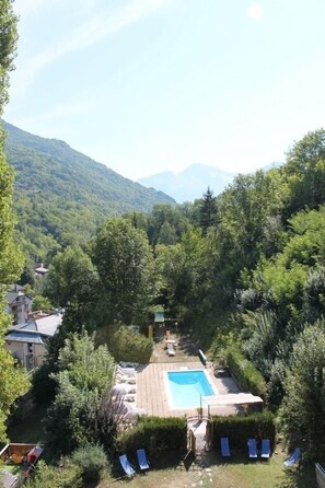 Una piscina rodeada de abundante vegetación, con montañas al fondo.