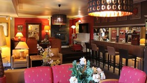 Vestíbulo de hotel con zona de bar, asientos y chimenea.