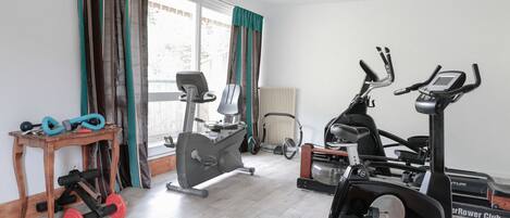 Un gimnasio en casa con una elíptica, una bicicleta estática y un banco de pesas.