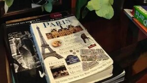 Un livre intitulé « Paris », contenant une carte et des photos de monuments emblématiques, une grande pivoine rose et une photographie encadrée de la Tour Eiffel.