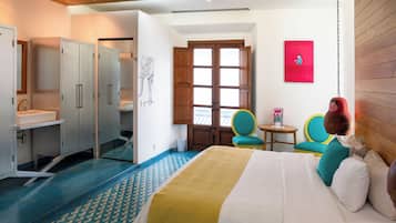 Una habitación de hotel con cama, escritorio, silla, mesita y ventana.