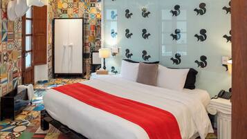 Una habitación de hotel con una cama grande, un armario, un escritorio con lámpara y una pared decorada con motivos de animales.