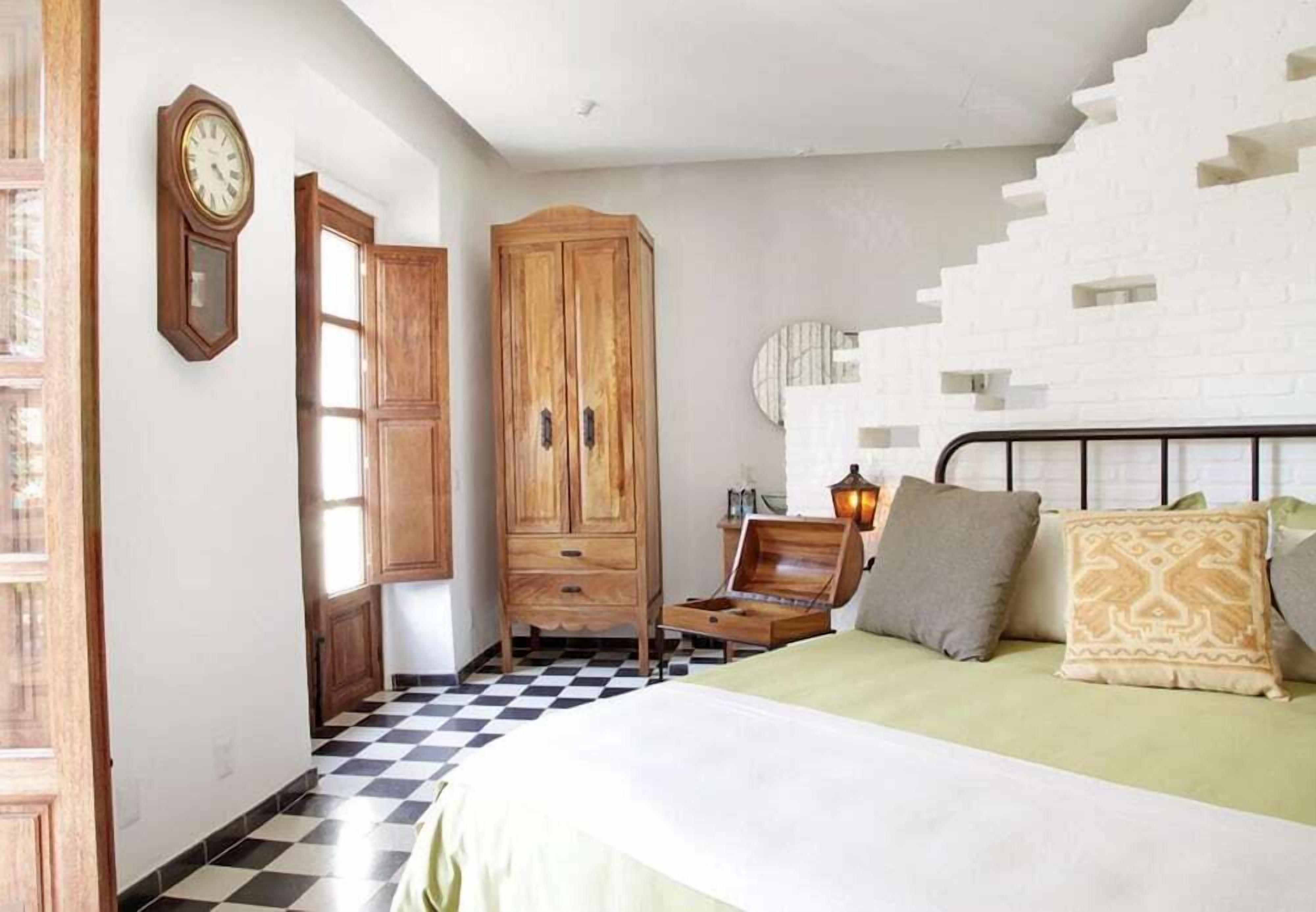 Een slaapkamer met een bed, een houten garderobe en een geruite vloer.
