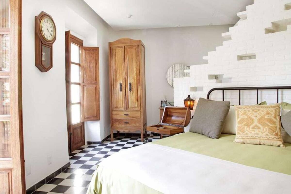A bedroom with a bed, wooden wardrobe, and a checkered floor.