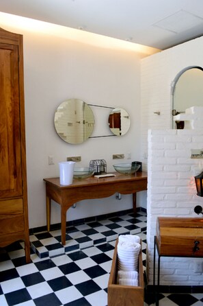 A bathroom with a checkered floor, wooden vanity, and a mirror with a round frame.