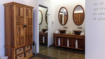 Baño con armarios de madera, un lavamanos y dos espejos.