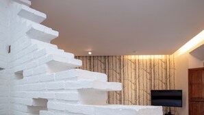 A staircase with white steps, a wall with vertical lines, and a flat-screen TV mounted on the wall. - Del Carmen Concept Hotel (Guadalajara)