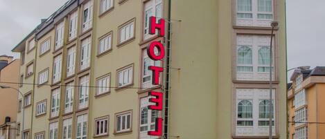Un hôtel à plusieurs étages, reconnaissable à son grand panneau « HÔTEL » sur la façade, qui présente un style architectural classique avec de grandes fenêtres et un toit plat.