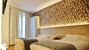A hotel room with two beds, a wardrobe, and a wall with a textured pattern. - Hospedium Hotel La Marina (Cee)