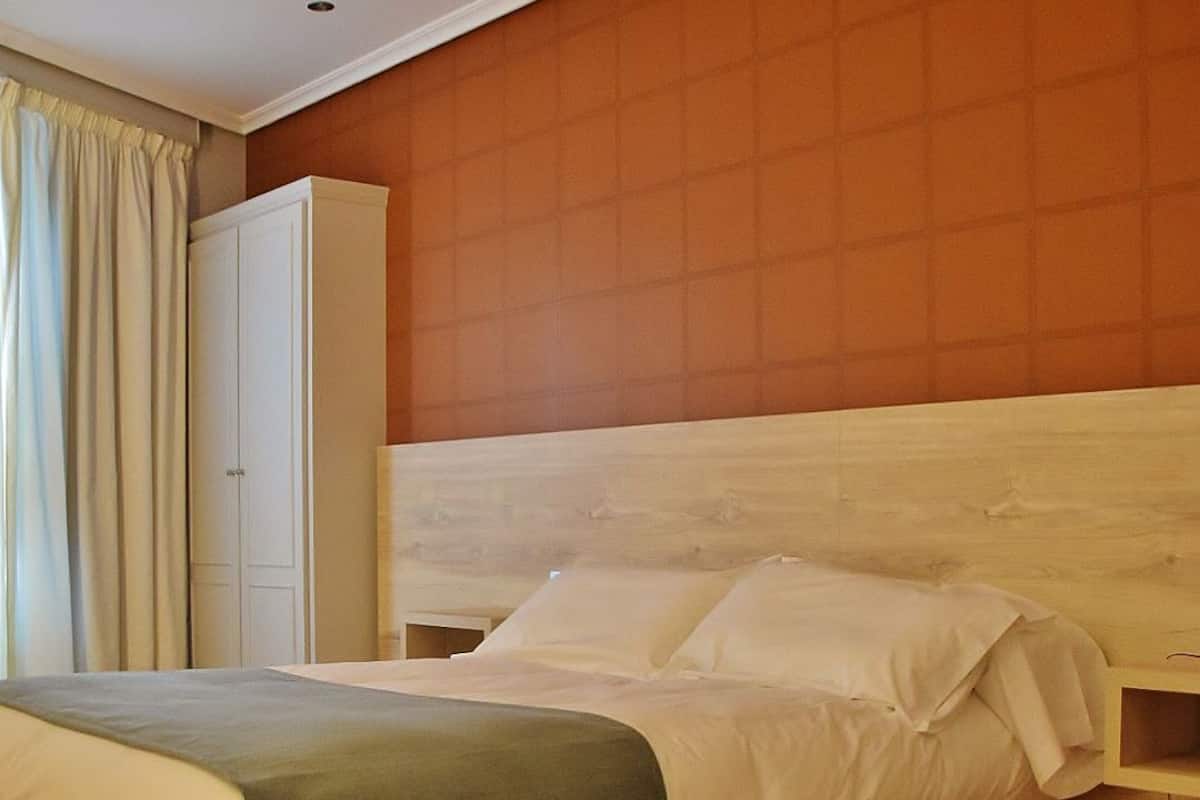 Un dormitorio con cama, armario y suelo de madera.
