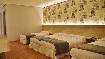Three beds are arranged in a row, each with white bedding and a throw blanket. A nightstand with a telephone is positioned between them.