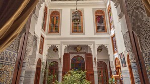 Un interior ornamentado con detalles intrincados en azulejos, ventanas arqueadas y un candelabro central.