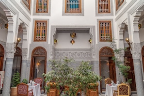 An interior courtyard with ornate arches, patterned walls, and a central seating area with tables and chairs. - Riad Tahra & Spa (Fes)