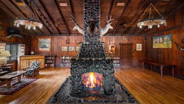 Una chimenea de piedra con astas, paredes de madera y techo de madera.