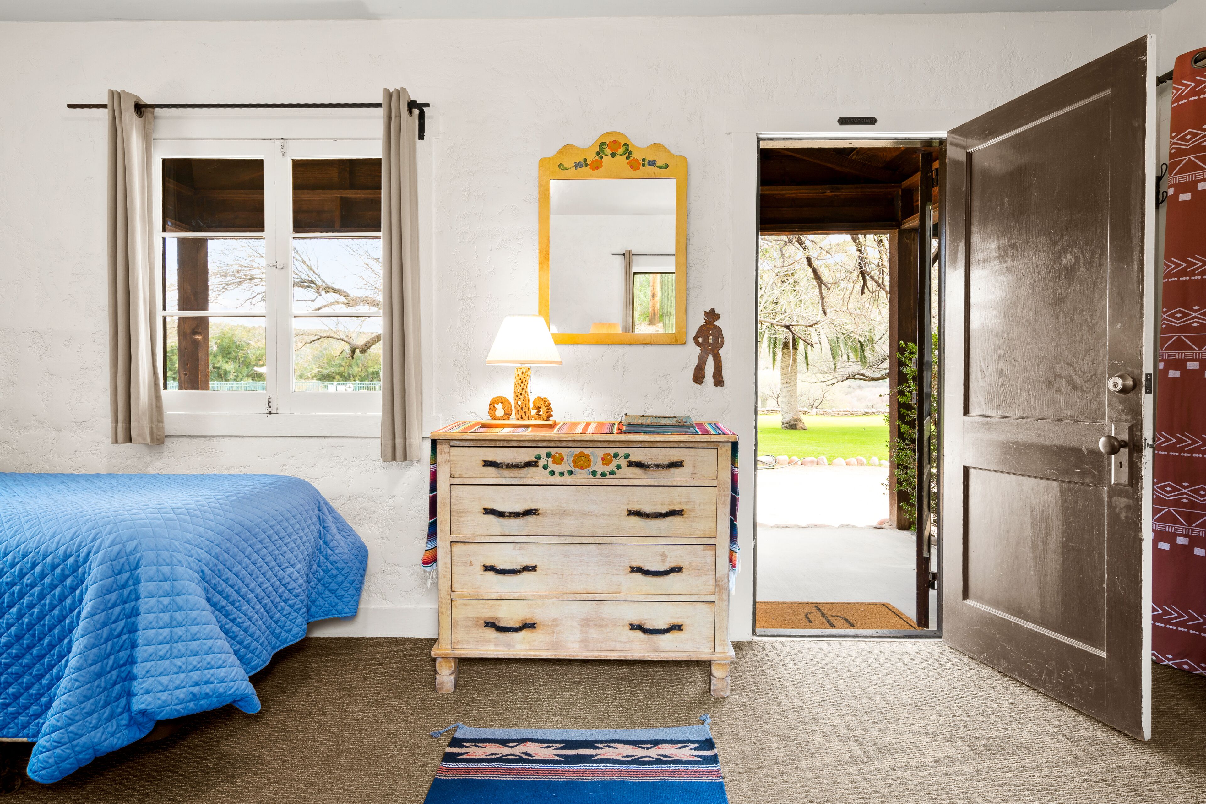 Un dormitorio con cama, cómoda, espejo y puerta que da a un balcón.