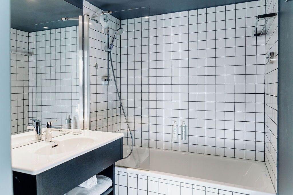 Ein modernes Badezimmer mit Dusche, Waschbecken und Spiegel.
