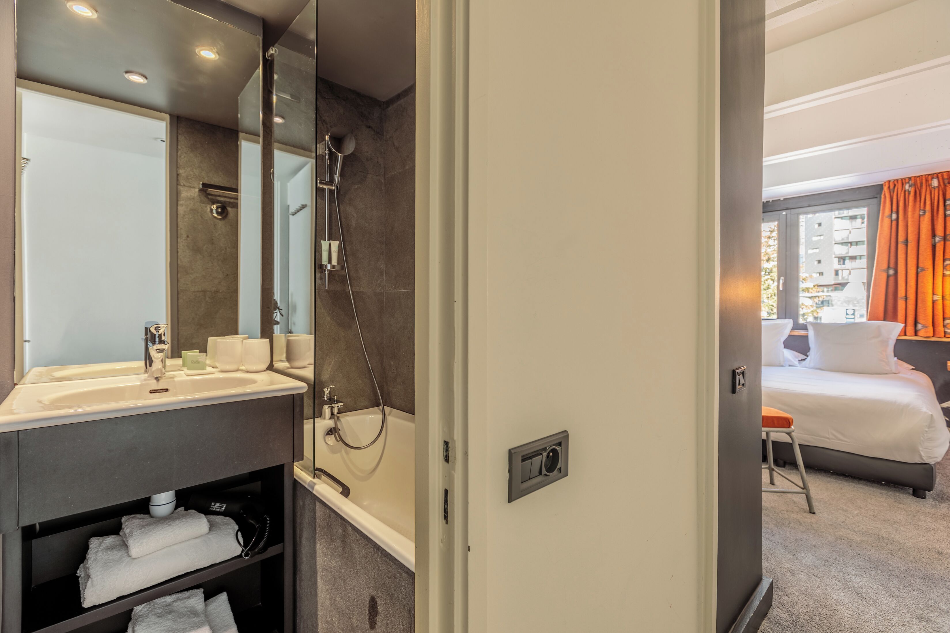 A modern bathroom with a bathtub, a large mirror, and a sink.