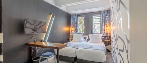 A modern bedroom with a bed, bedside tables, a desk, and a chair.