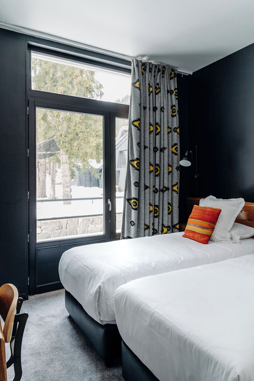 Habitación de hotel con dos camas, un ventanal grande y vistas al exterior.
