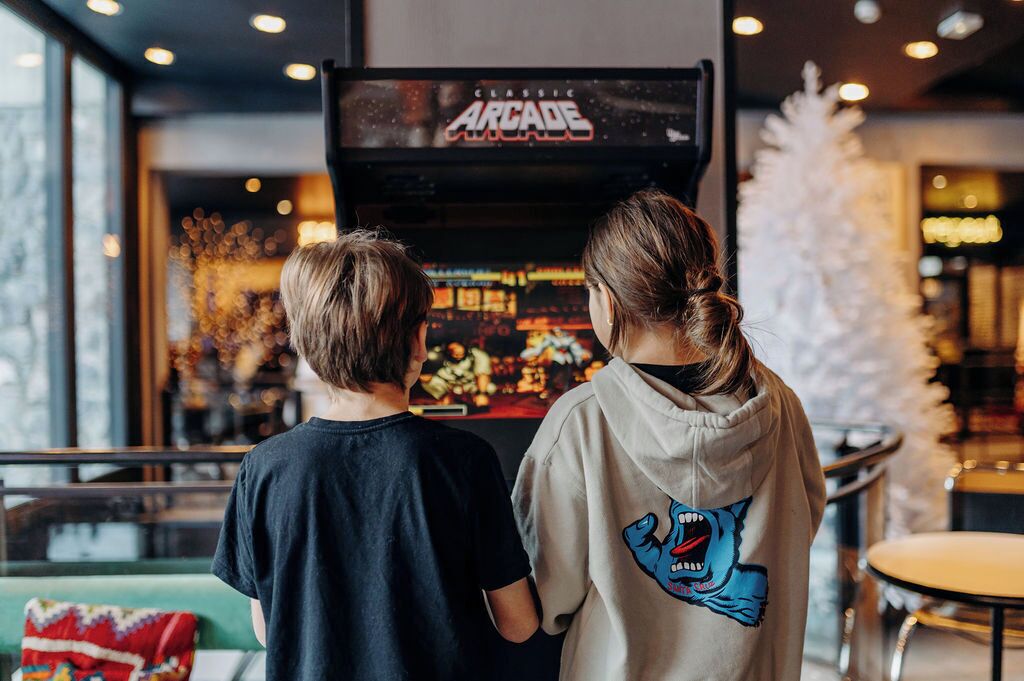 Two people standing in front of a classic arcade machine.