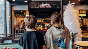 Two people standing in front of a classic arcade machine.
