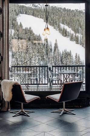 A balcony with two modern chairs and a hanging light fixture, overlooking a snowy mountain landscape. - Totem, Friendly Hotel (Araches-la-Frasse)