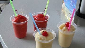 Trois gobelets en plastique contenant des boissons et des pailles, posés sur une table.