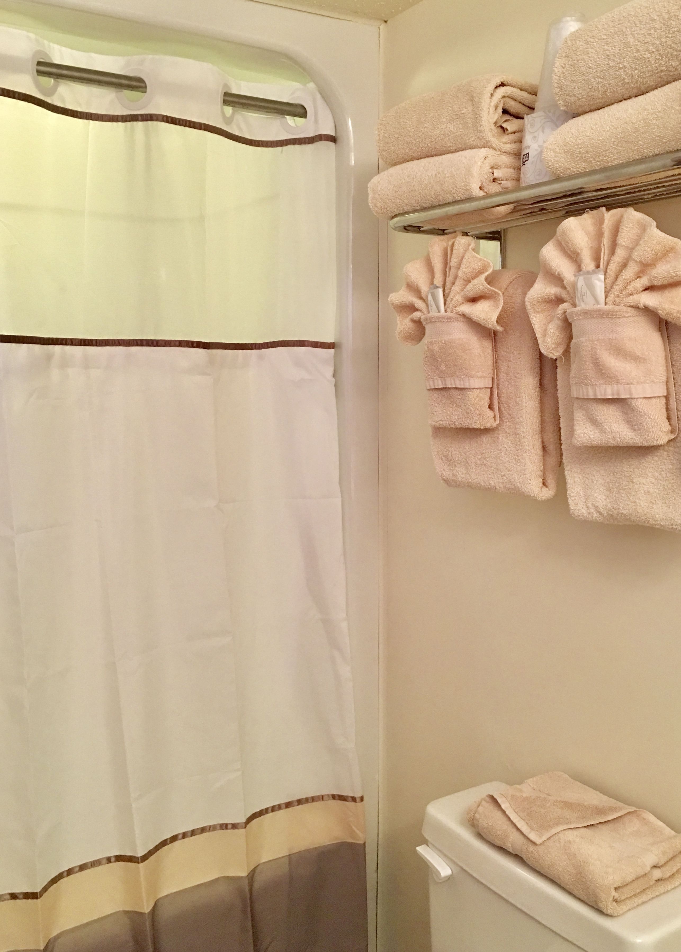 A bathroom with a shower curtain, a toilet, and towels on a rack.