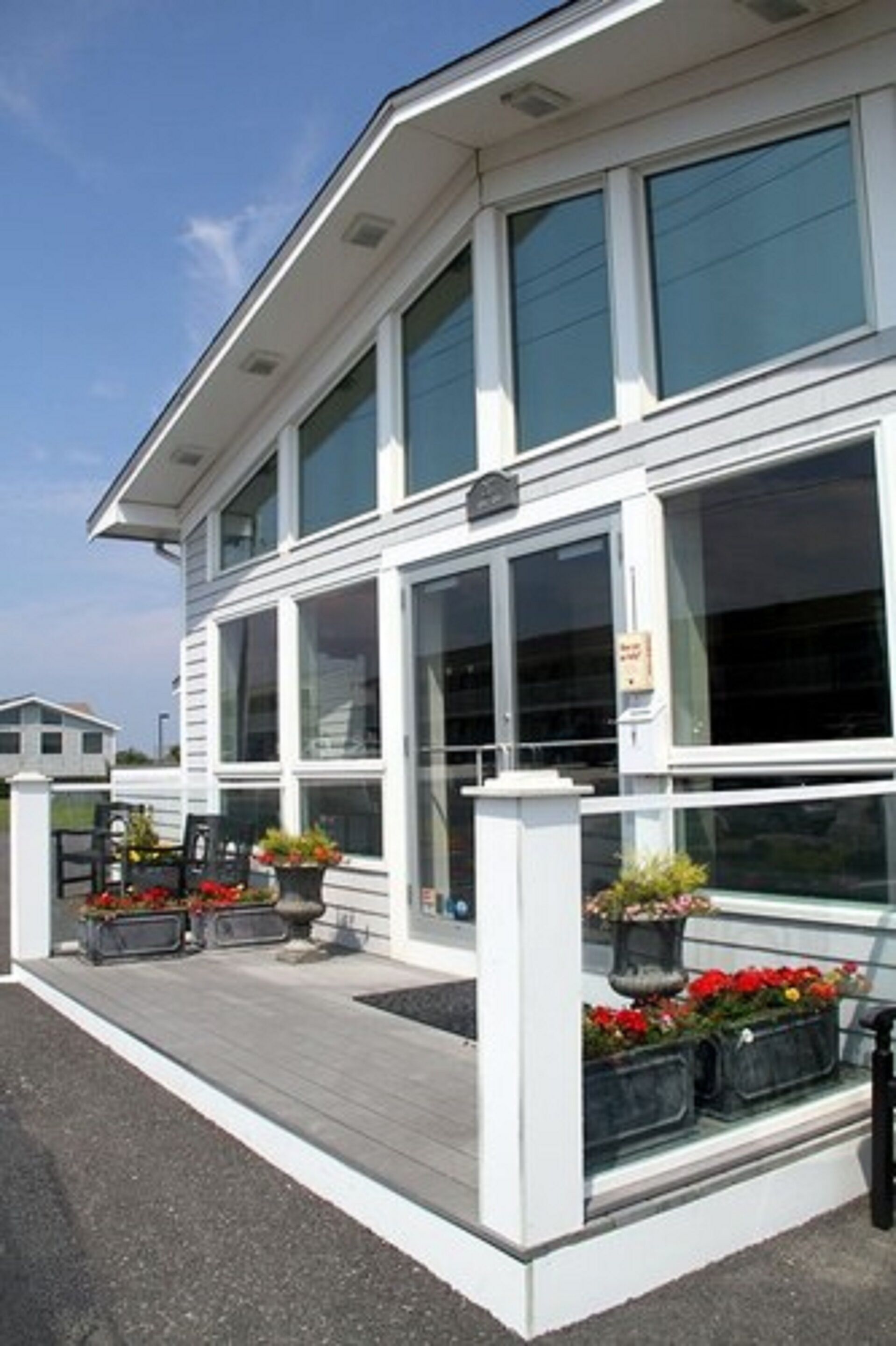 A two-story building with large windows and a covered outdoor area with planters.