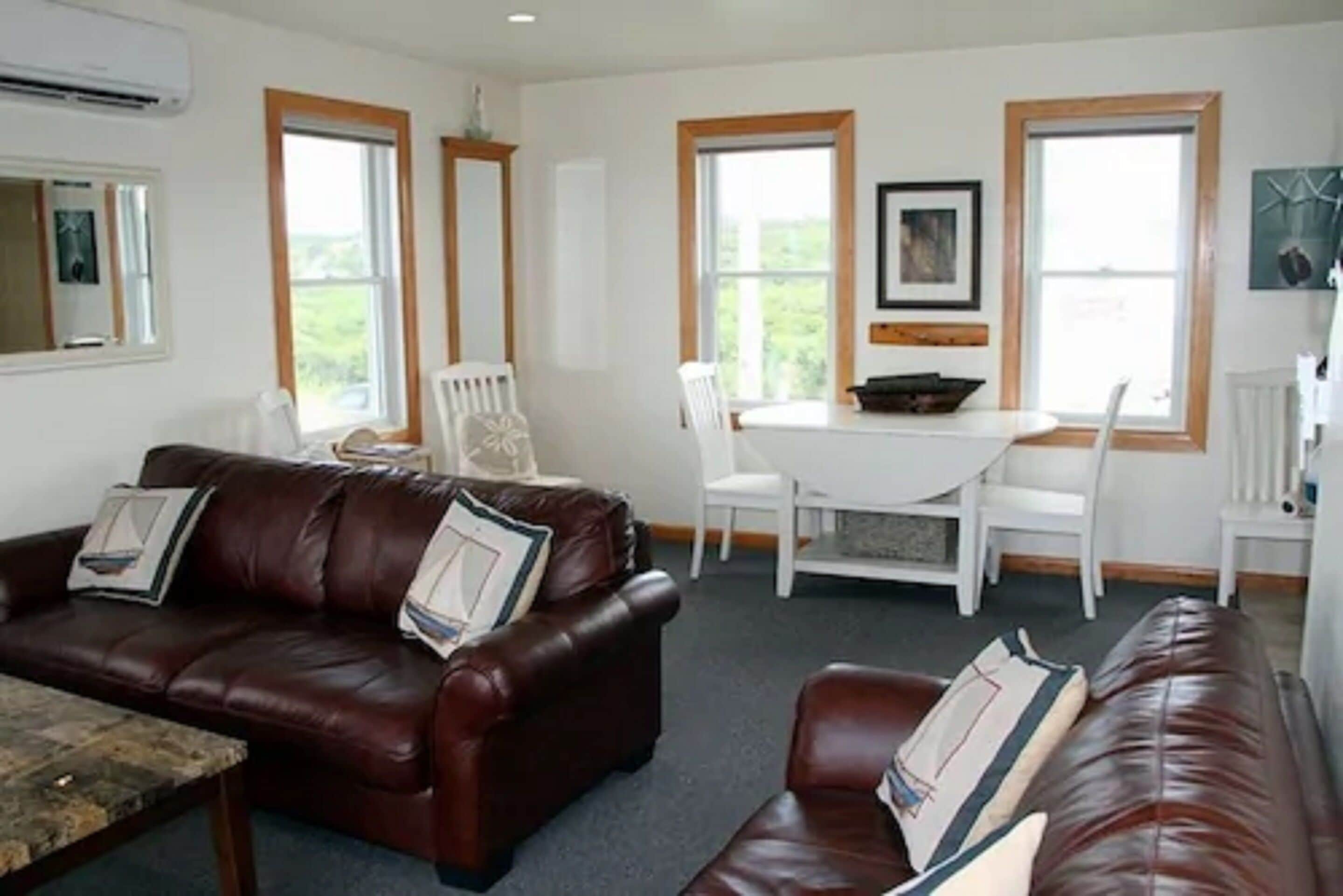 A living room with a brown leather sofa, a coffee table, and a dining table with chairs.