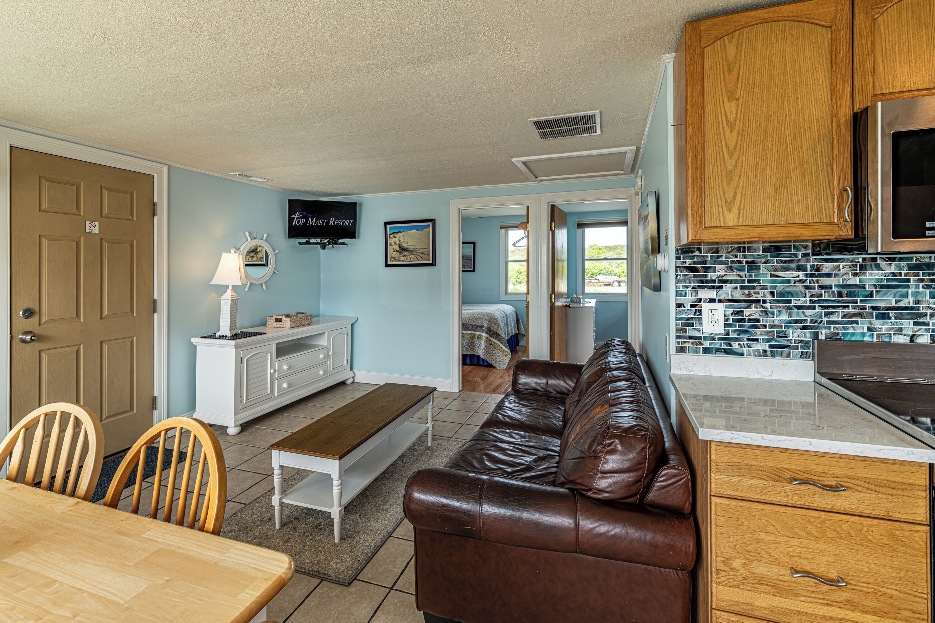 A compact living space with a kitchenette, a dining area, and a bedroom.