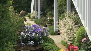 A garden with a small waterfall, various plants, and a white staircase leading to a building. - Top Mast Resort (North Truro)