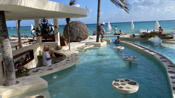 Un espace piscine doté d’un bar, de chaises longues et offrant une vue sur l’océan.