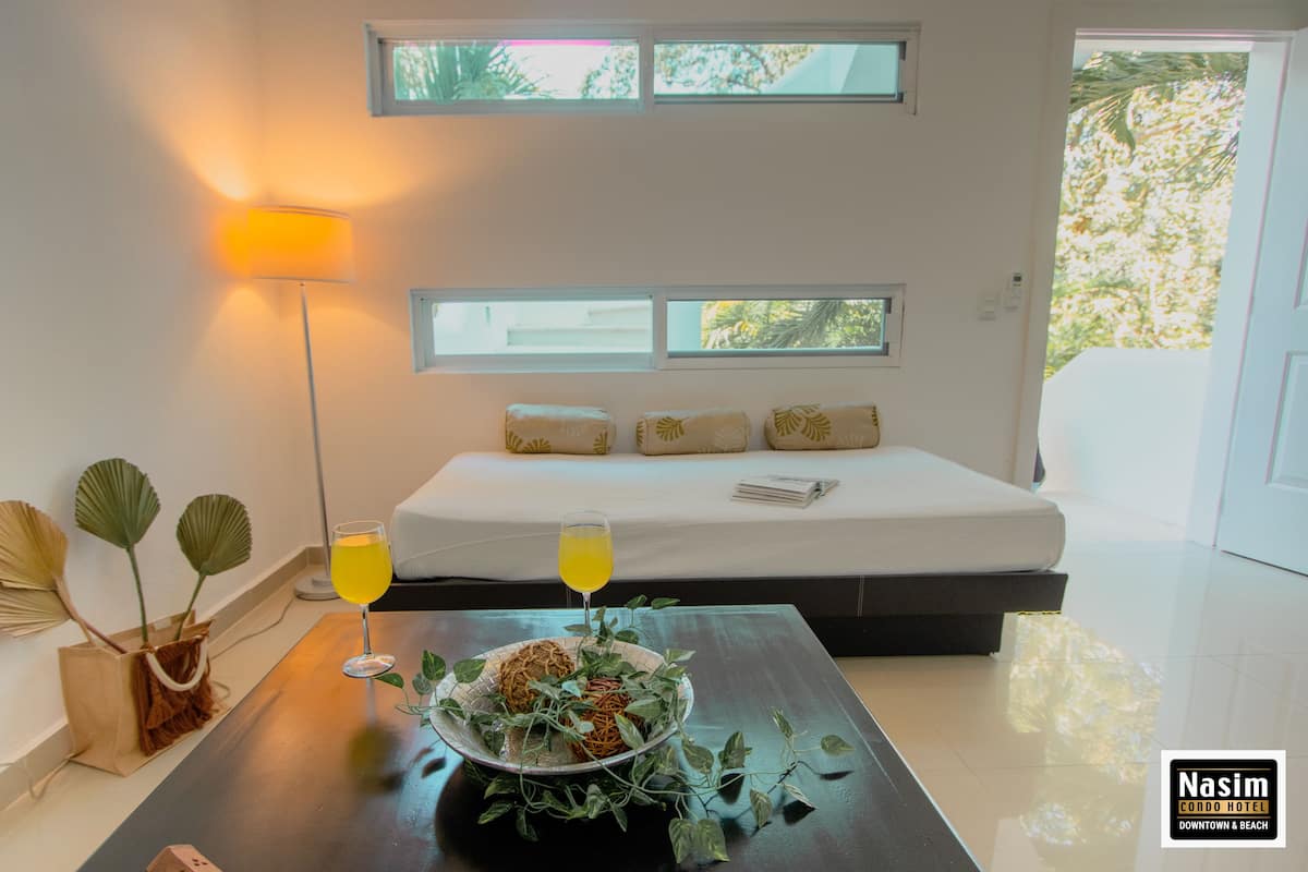Ein modernes Schlafzimmer mit Bett, Nachttischen, einer Lampe und Blick ins Freie.