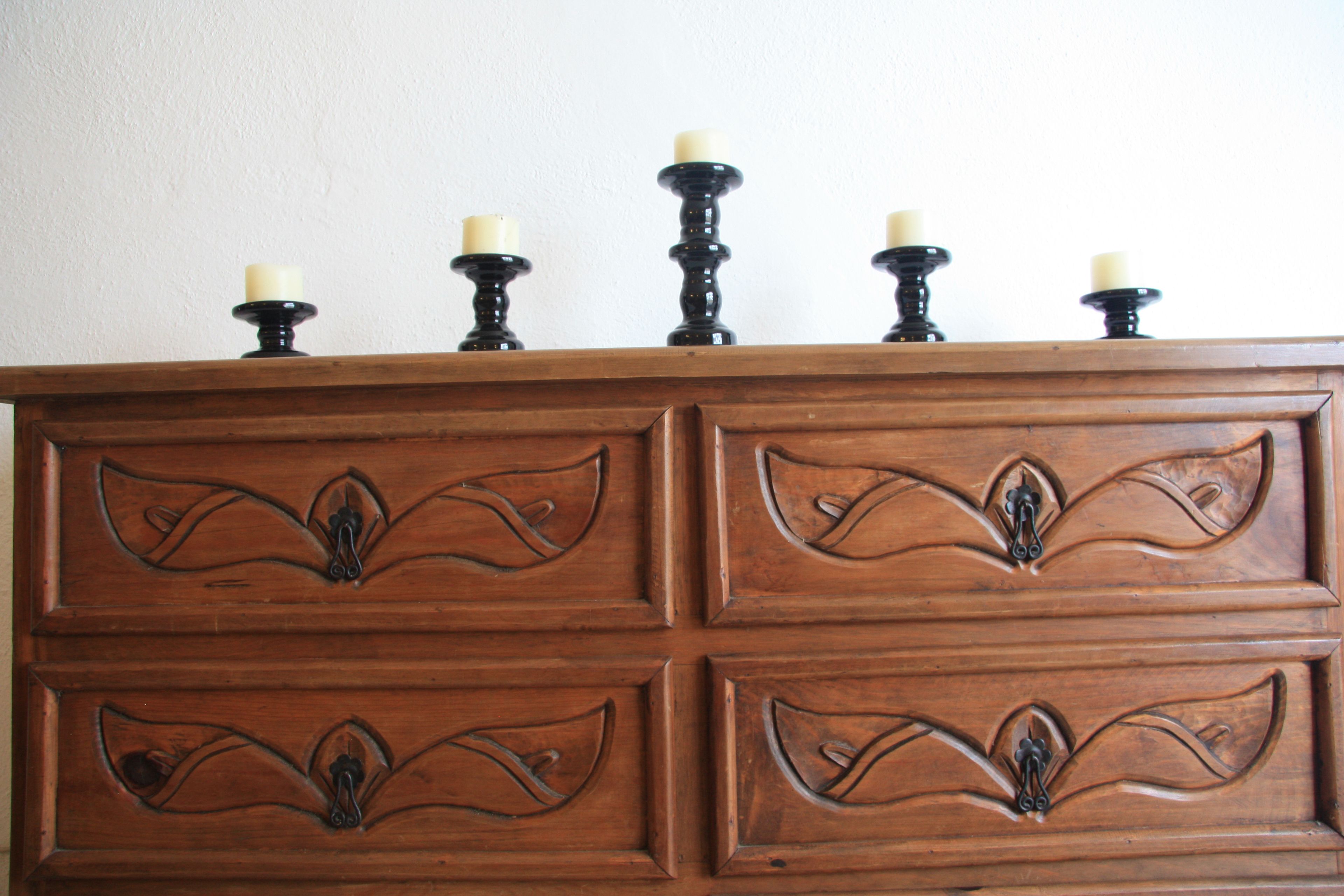 Une commode en bois avec quatre tiroirs et un plateau supérieur muni de cinq porte-bougies.