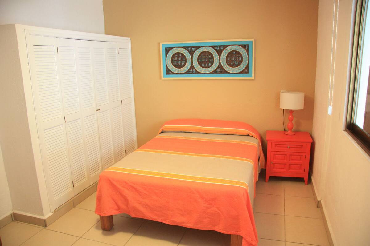 Une chambre à coucher comprenant un lit, une armoire, une table de chevet et un climatiseur fixé au mur.