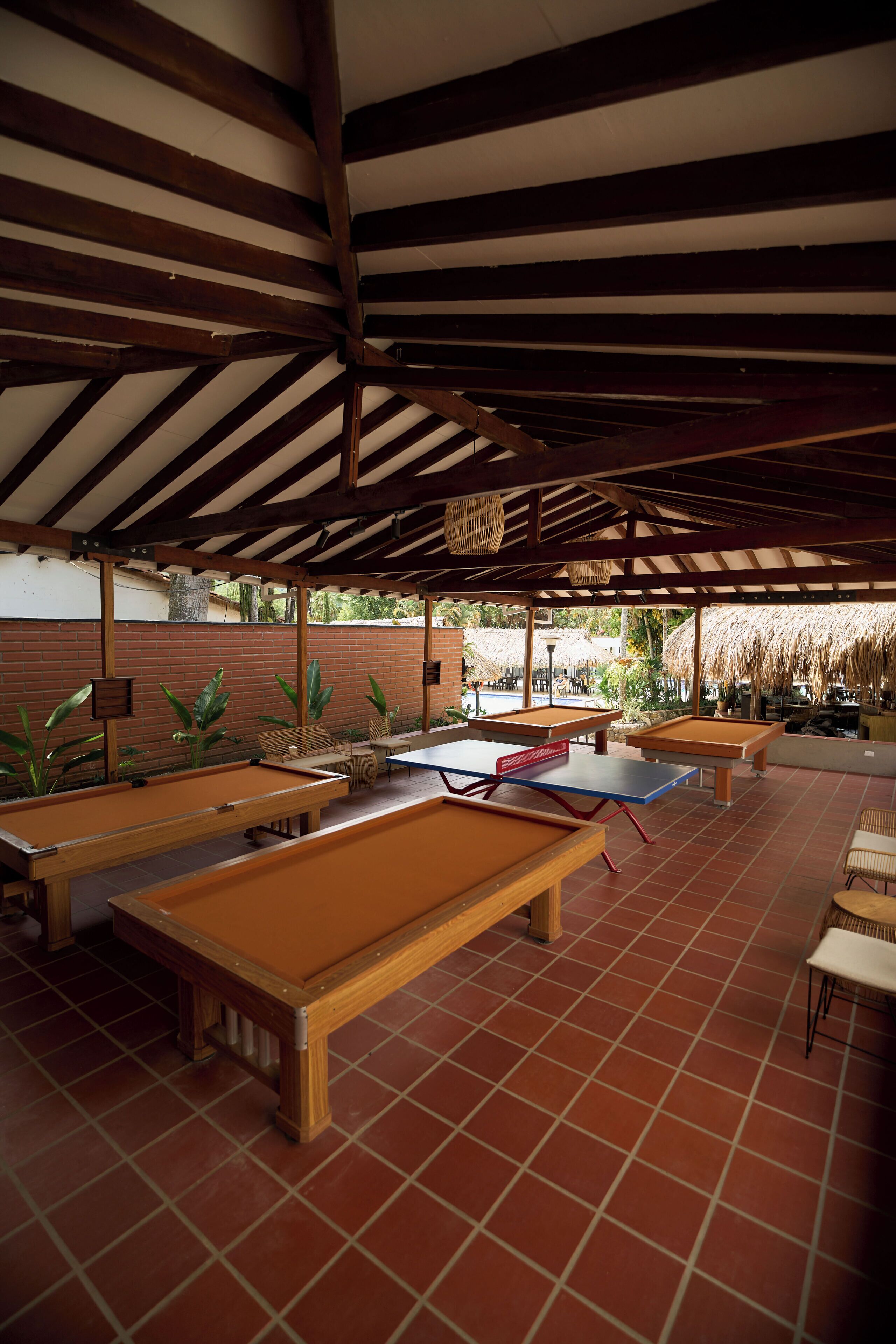 A covered outdoor area with multiple pool tables and chairs.