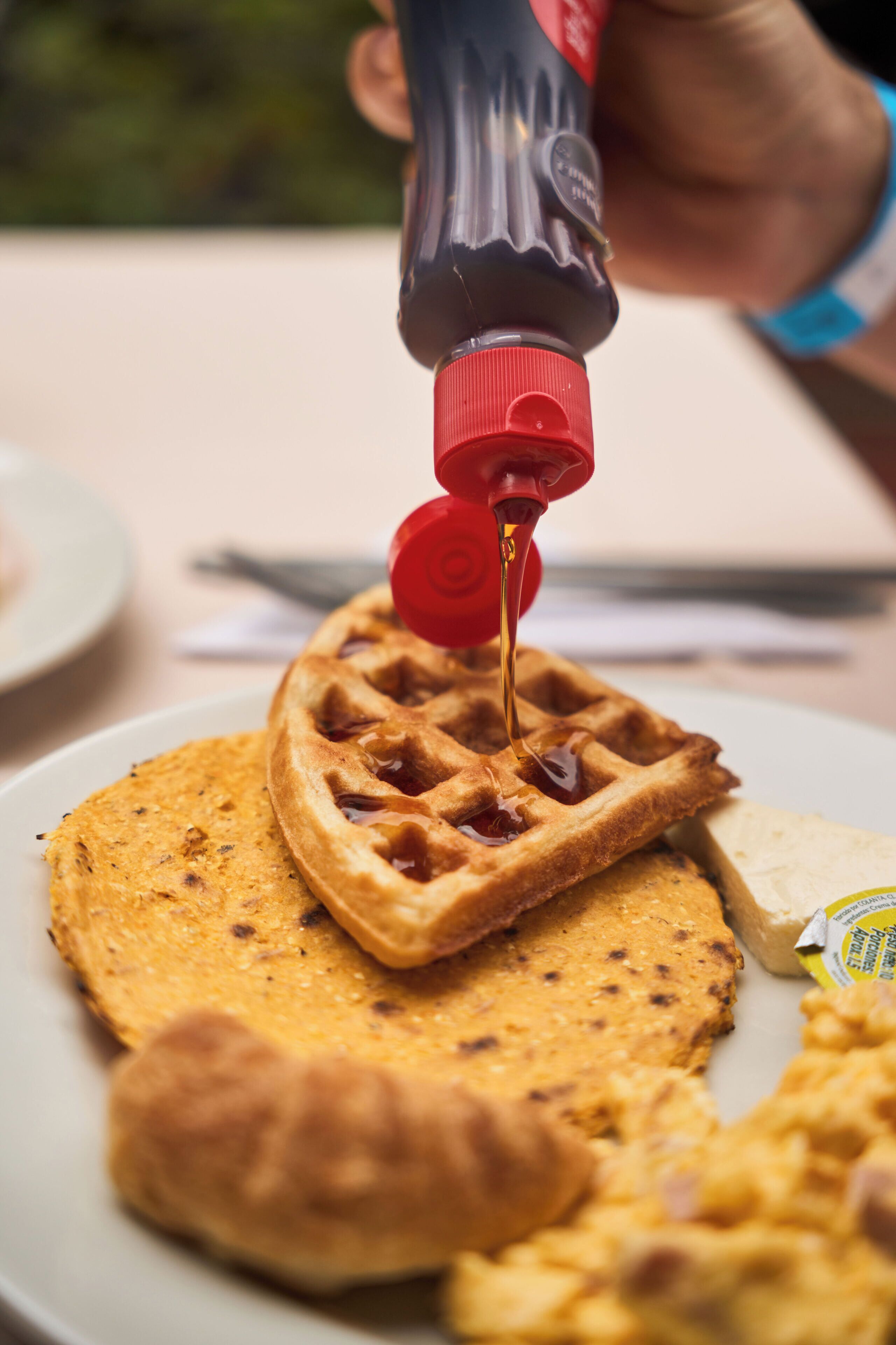 A waffle being topped with syrup.