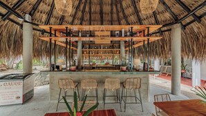A bar with a thatched roof, wooden bar counter, and wicker chairs. - Hotel Quimbaya (San Jerónimo)