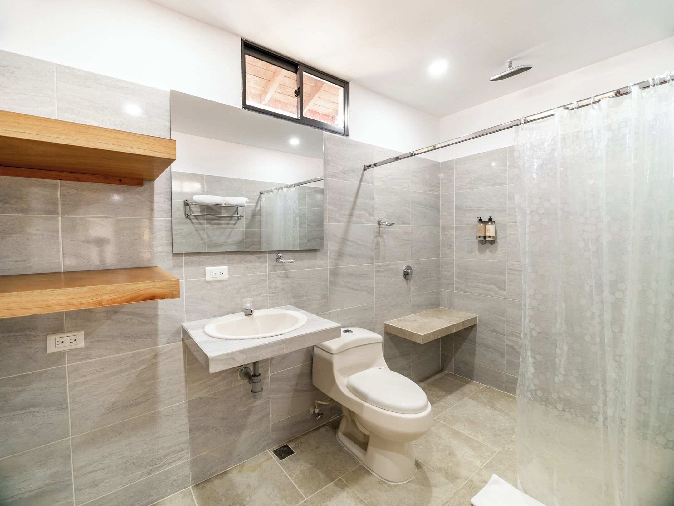 Une salle de bain moderne avec deux lavabos, des toilettes, une douche et une étagère en bois.