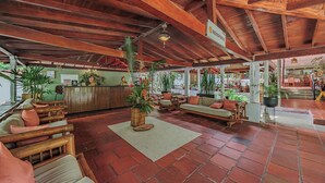 A spacious lobby with wooden furniture, a reception desk, and potted plants. - Hotel Quimbaya (San Jerónimo)