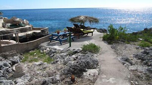 A coastal view with a pathway leading to a seating area with tables and chairs, overlooking the sea. - Sundown Villa -Negril (Negril)