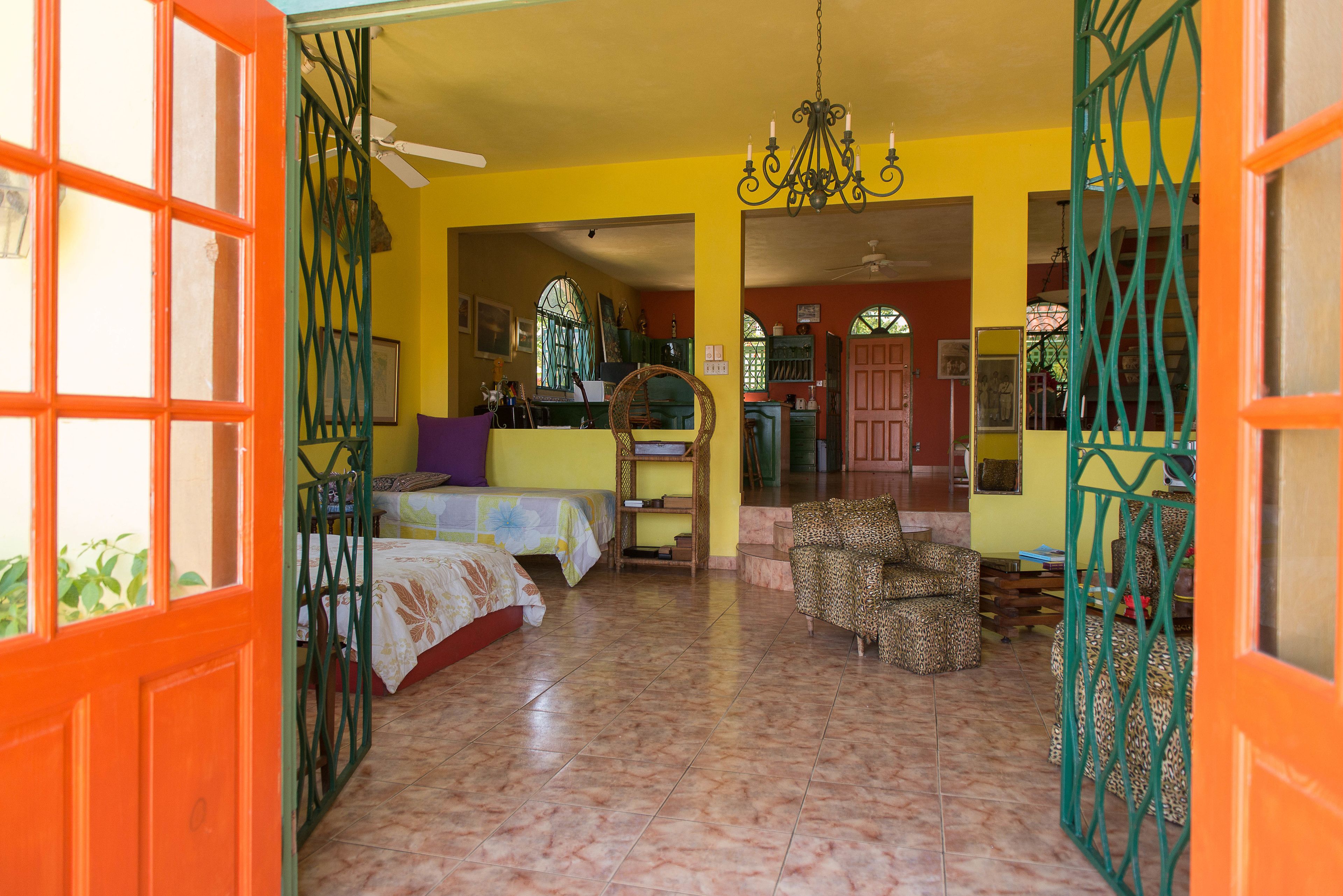A room with two beds, a sofa, and a chair. There is a chandelier and a ceiling fan.
