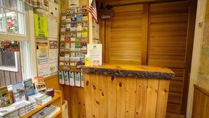 Un mostrador de recepción de madera con una barra, rodeado de estanterías llenas de libros y revistas.