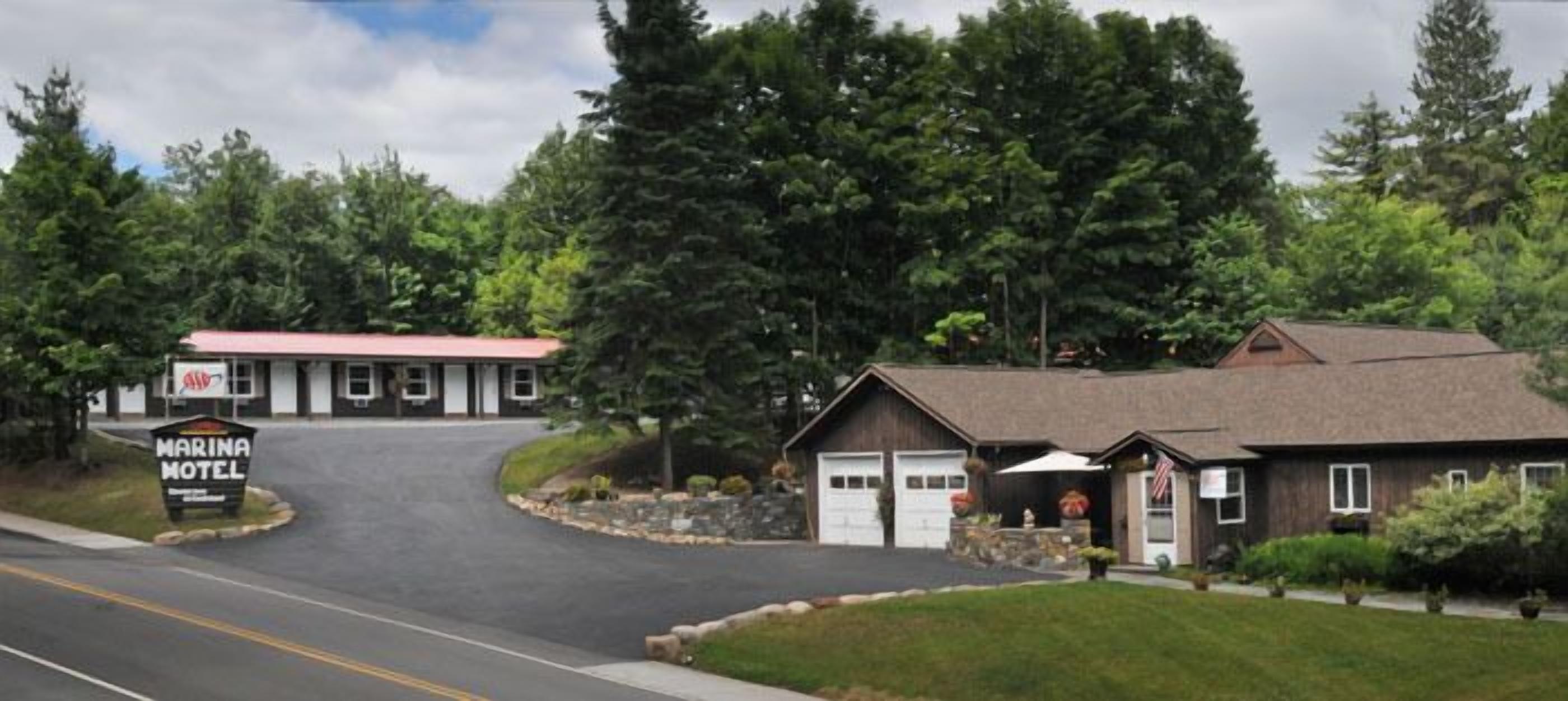 A marina motel with a red roof, a large sign, and a building with a brown roof and garage doors.