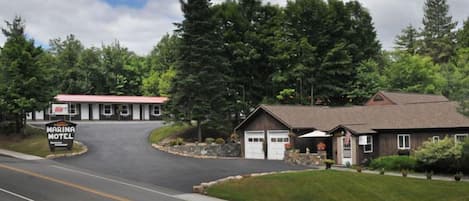 A marina motel with a red roof, a large sign, and a building with a brown roof and garage doors.