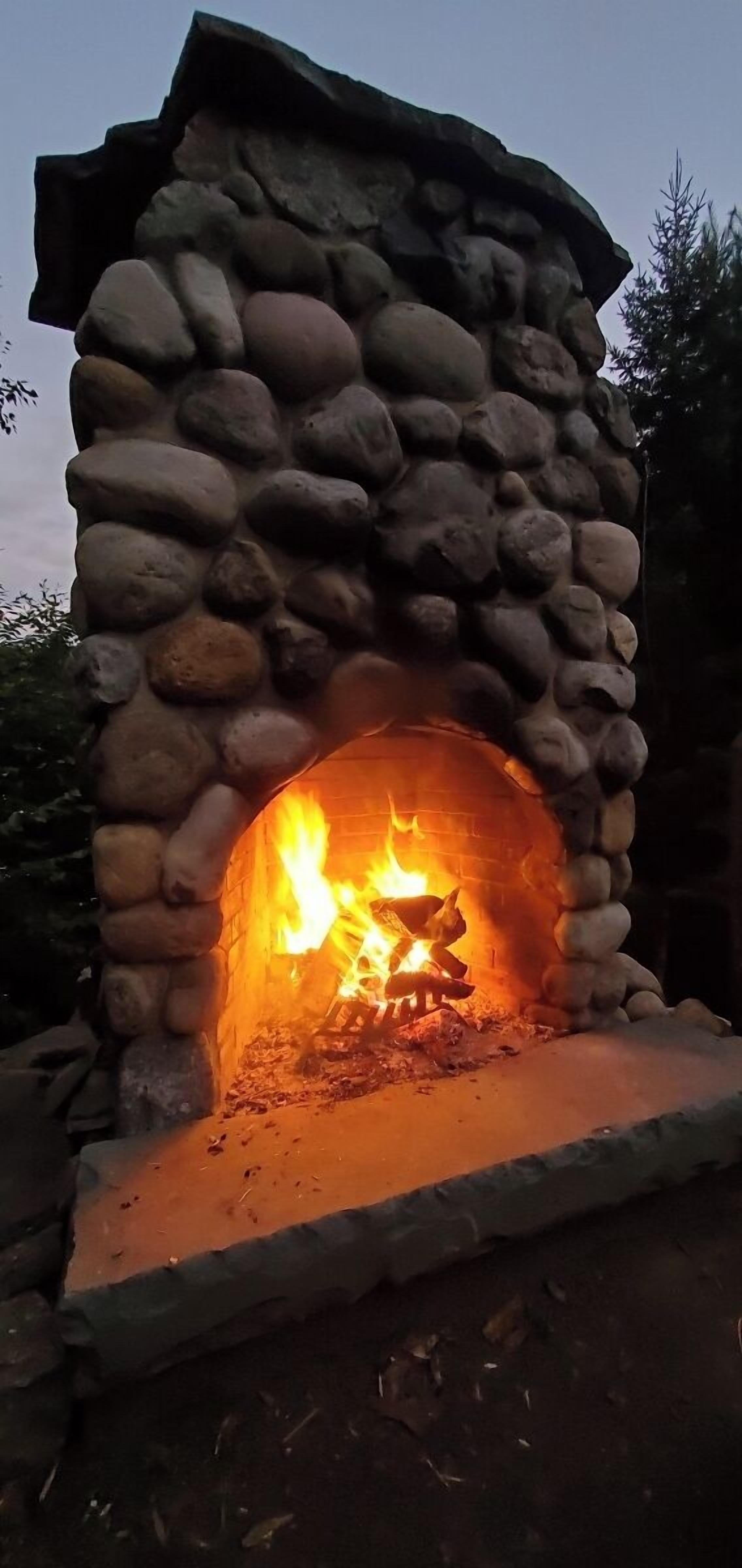 A stone-built fireplace with a fire burning inside.