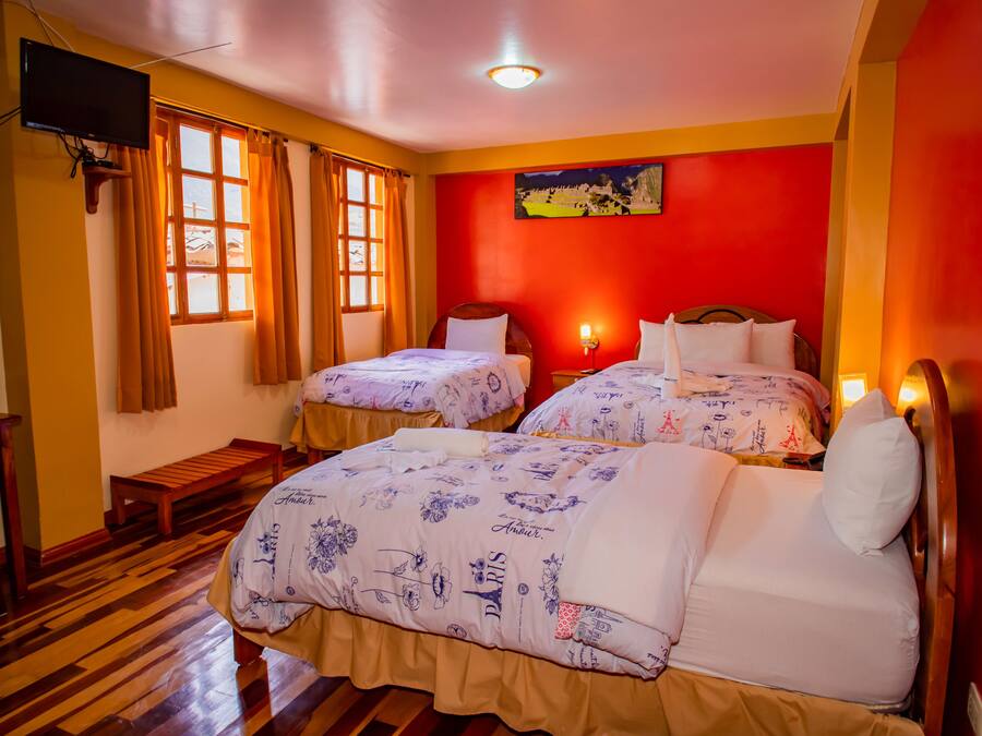 Une chambre d’hôtel avec deux lits, un plancher en bois, une télévision et un tableau au mur.
