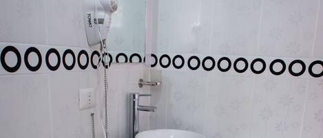 A bathroom with a toilet, a sink, and a hairdryer mounted on the wall.